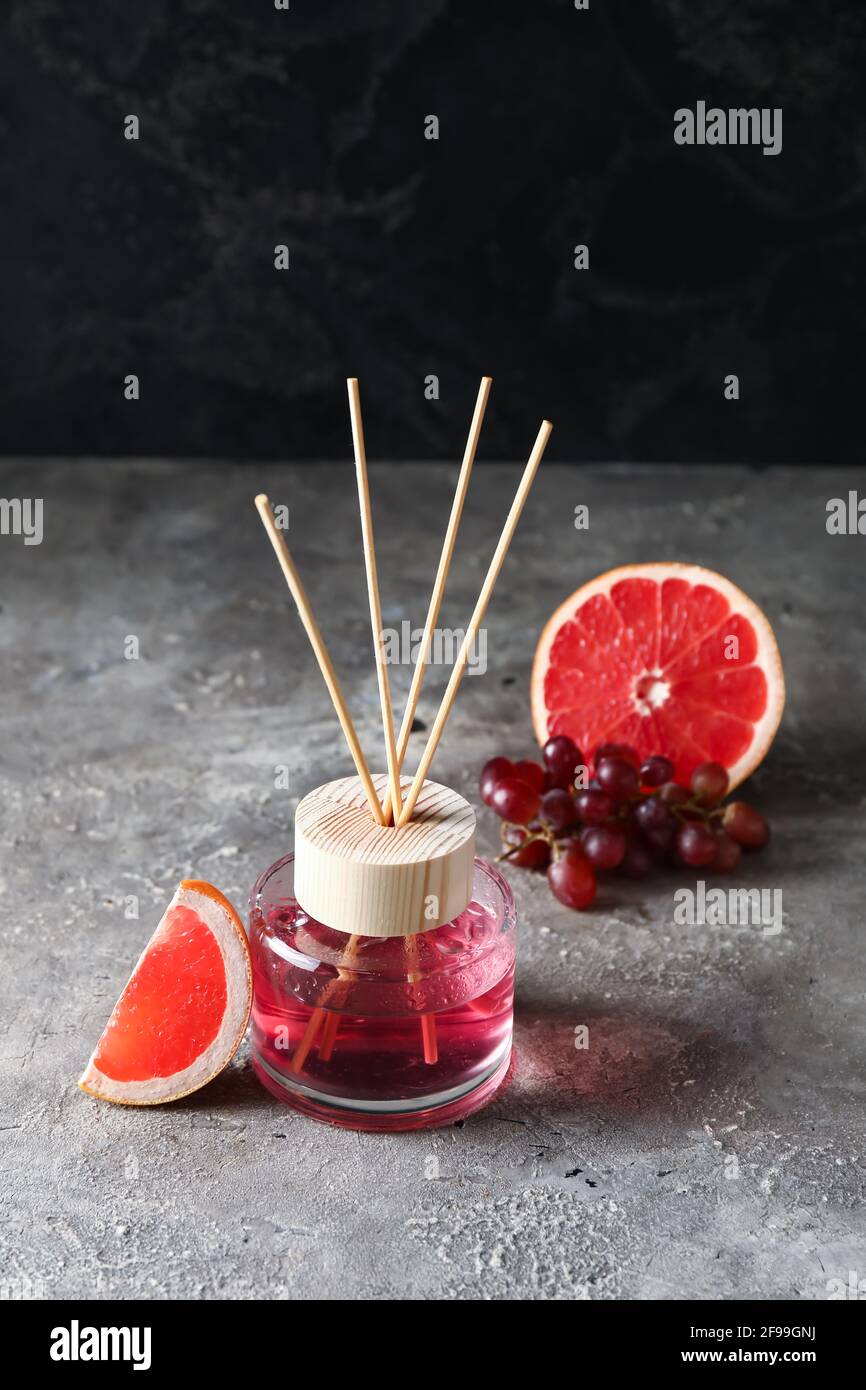 Reed diffuser with grapefruit and grapes on grunge background Stock Photo