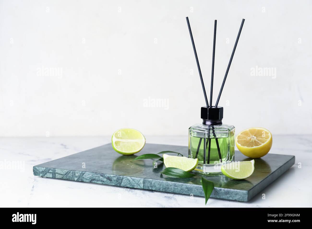 Reed diffuser with lemon and lime on light background Stock Photo