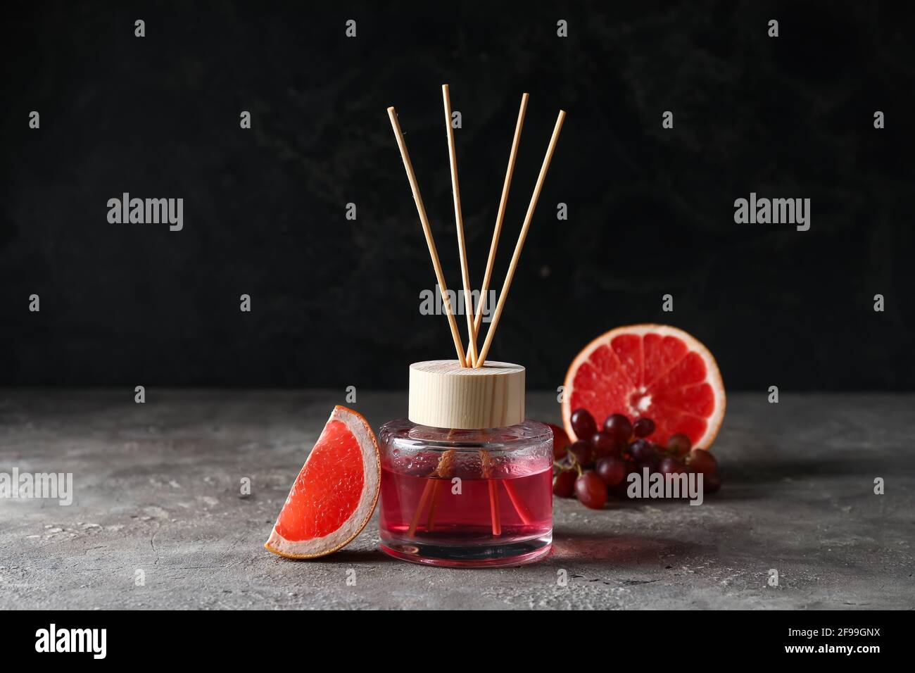 Reed diffuser with grapefruit and grapes on grunge background Stock Photo