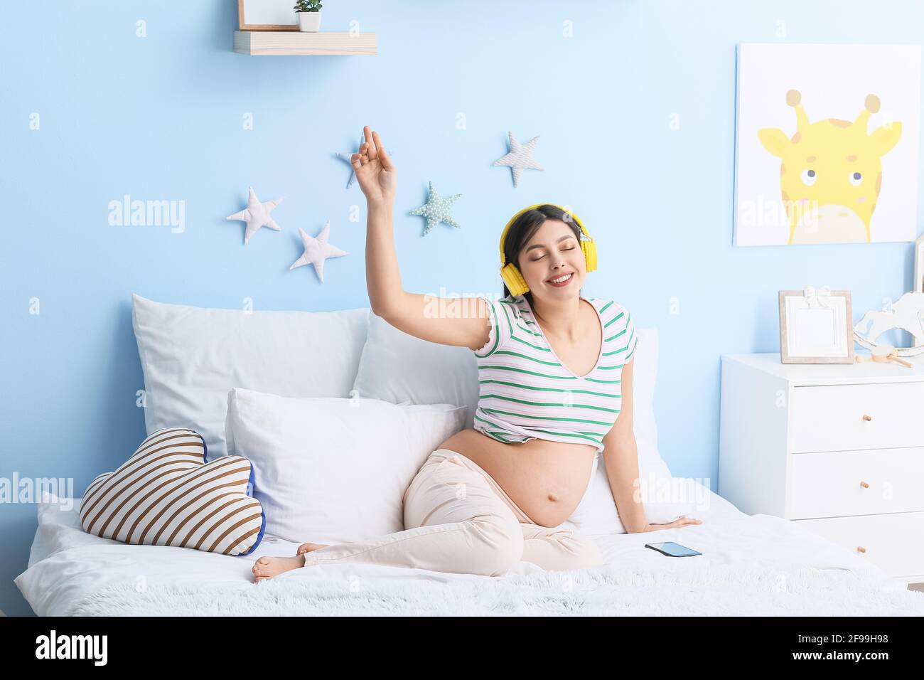 Young pregnant woman listening to music at home Stock Photo - Alamy