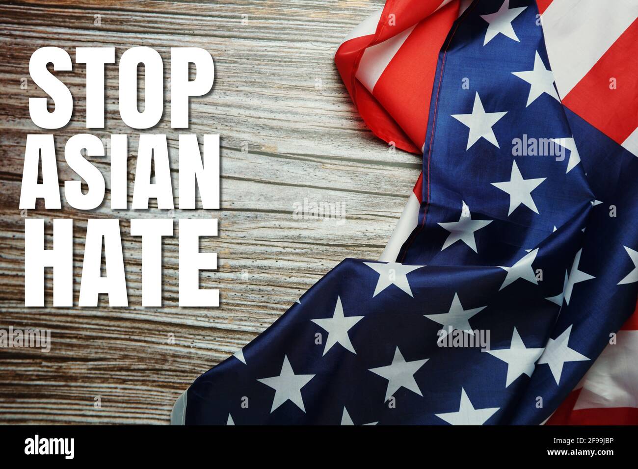 Stop Asian Hate text with USA flag on wooden background Stock Photo