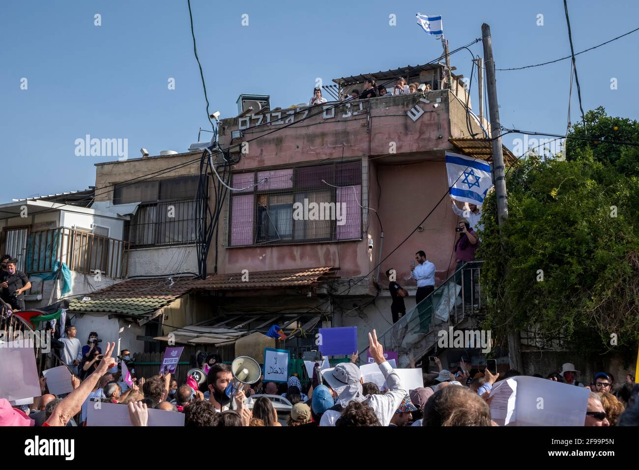 Israeli left-wing activists hold up placards in front of a house which was occupied by Jewish settlers during a demonstration against settlement activity in Sheikh Jarrah a predominantly Palestinian neighborhood on April 16, 2021, in East Jerusalem, Israel. The Palestinian neighborhood of Sheikh Jarrah is currently the center of a number of property disputes between Palestinians and Israelis. Some houses were occupied by Israeli settlers following a court ruling. Stock Photo