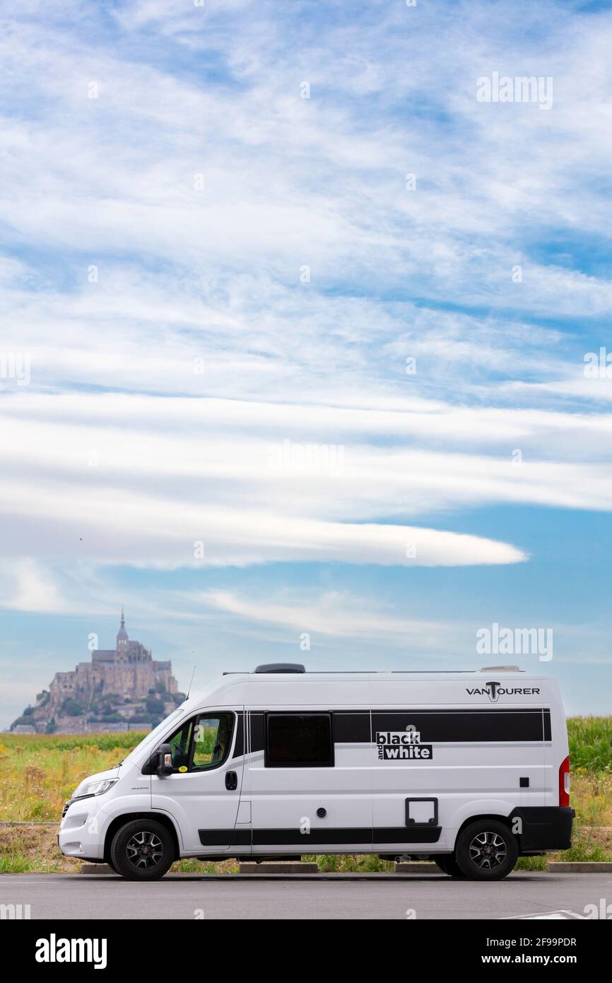 Motorhome / Van 'Vantourer Black and White' in front of the beautiful historic tidal island and fortress Le Mont-Saint-Michel. The monument is a UNESCO World Heritage Site in the Normandy, France Stock Photo
