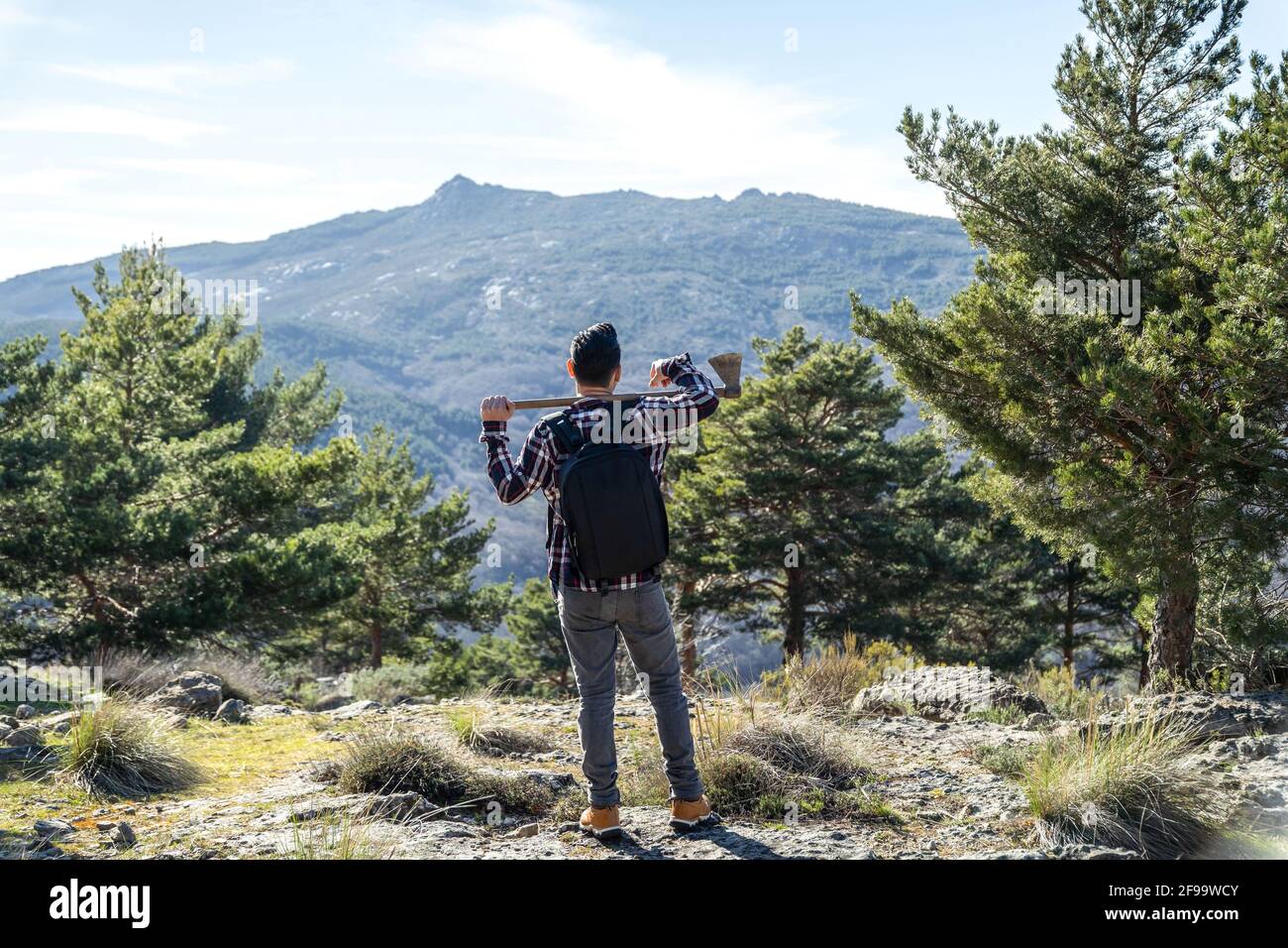 Spanish Lumberjack man with backpack and ax on his shoulder walking up