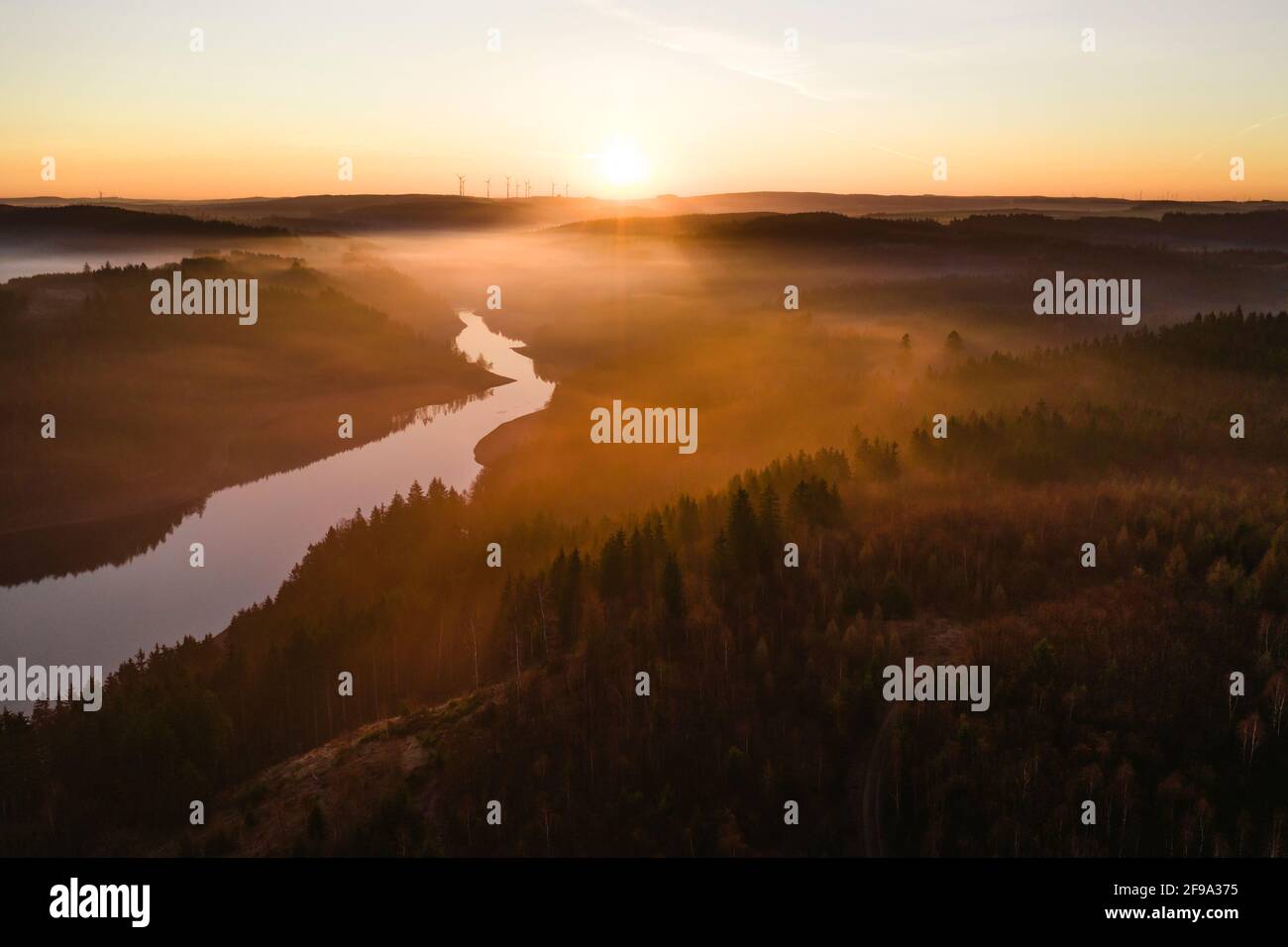 A single arm of the Bleilochtalsperre meanders through the forest in the direction of the rising sun Stock Photo