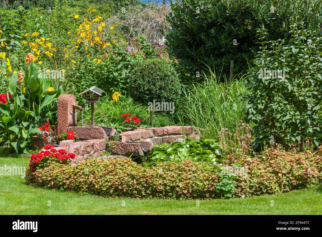 Germany, BadenWuerttemberg, garden pond with fountain and bird house