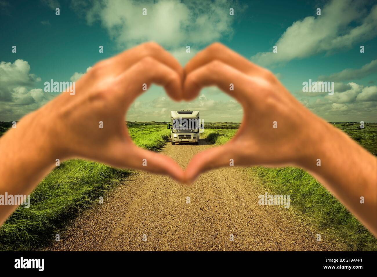 Motorhome on an off-road road seen through a heart hand Stock Photo