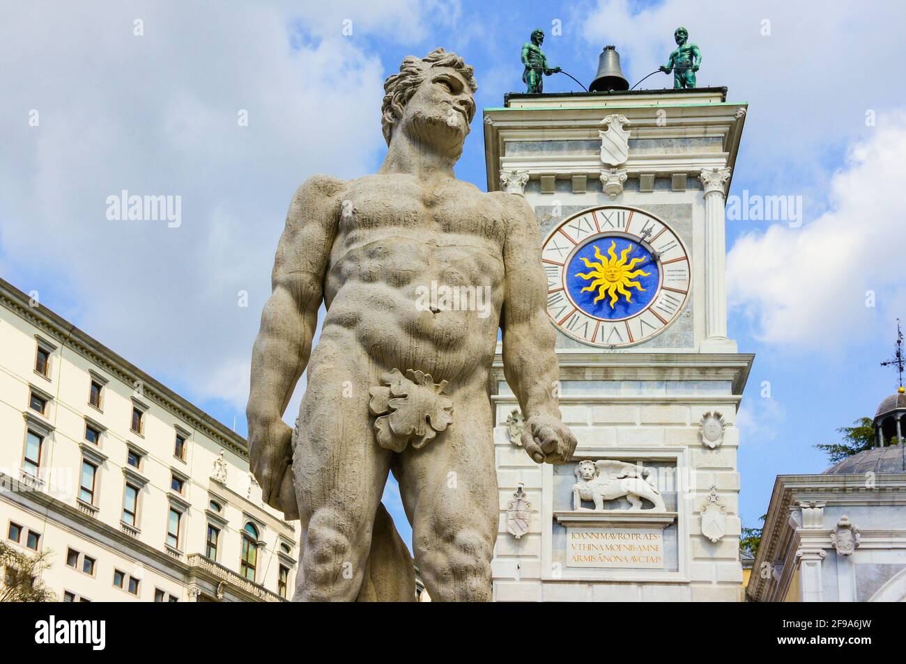 Udine, Italy (15h April 2021) - The statue of Hercules with the Clock Tower and an angle of the Castle in Piazza Libertà square Stock Photo