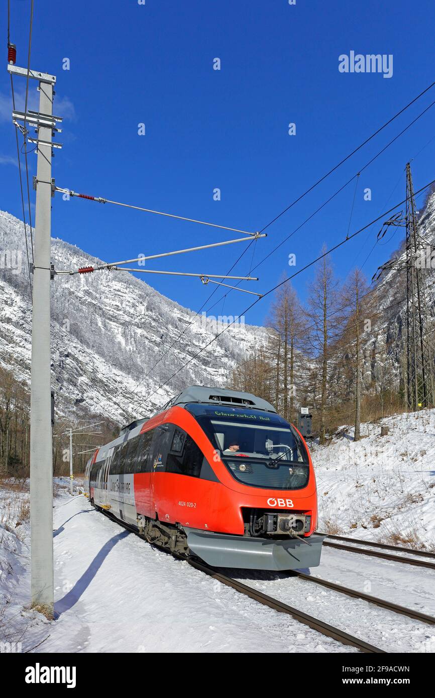 Passenger train of the ÖBB in Salzachtal in Pass Lueg in winter against blue sky in vertical format Stock Photo