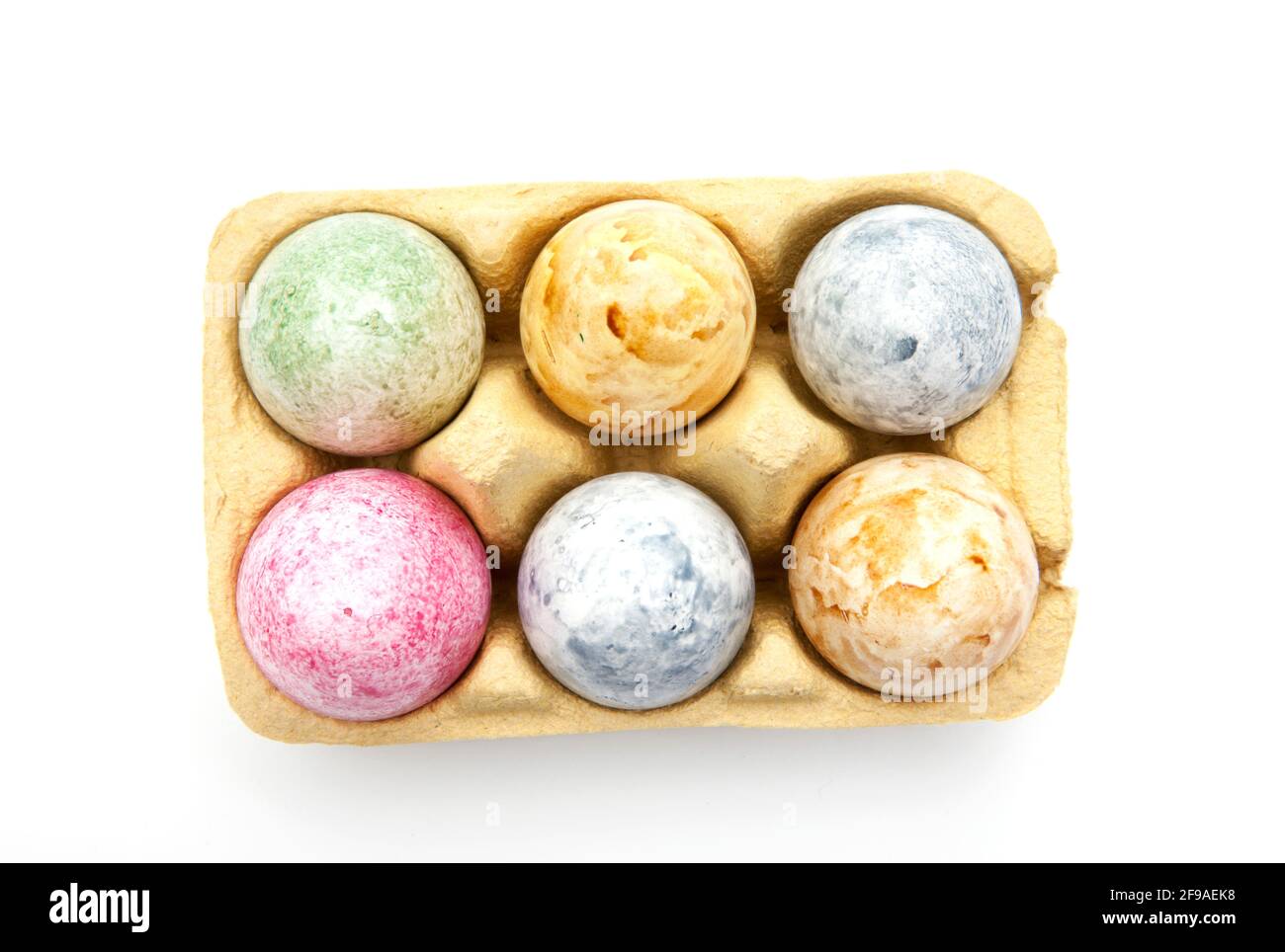 Brightly colored Easter eggs in an egg carton isolated on a white background Stock Photo