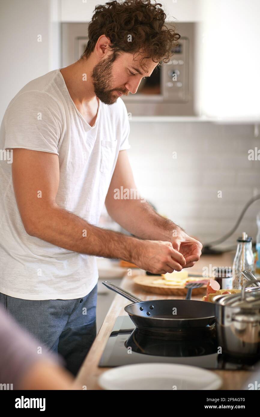 caucasian beardy guy with curly hair making breakfast. Stock Photo