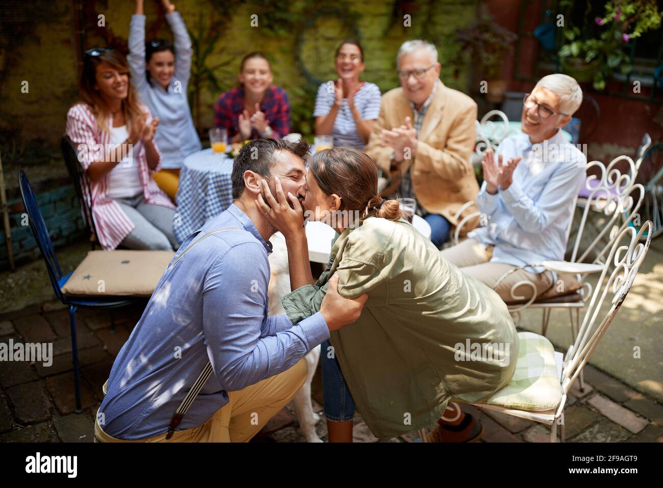 A group of friends of different generations congratulate on the engagement of their young friends at the party in a cheerful atmosphere in the bar. Le Stock Photo
