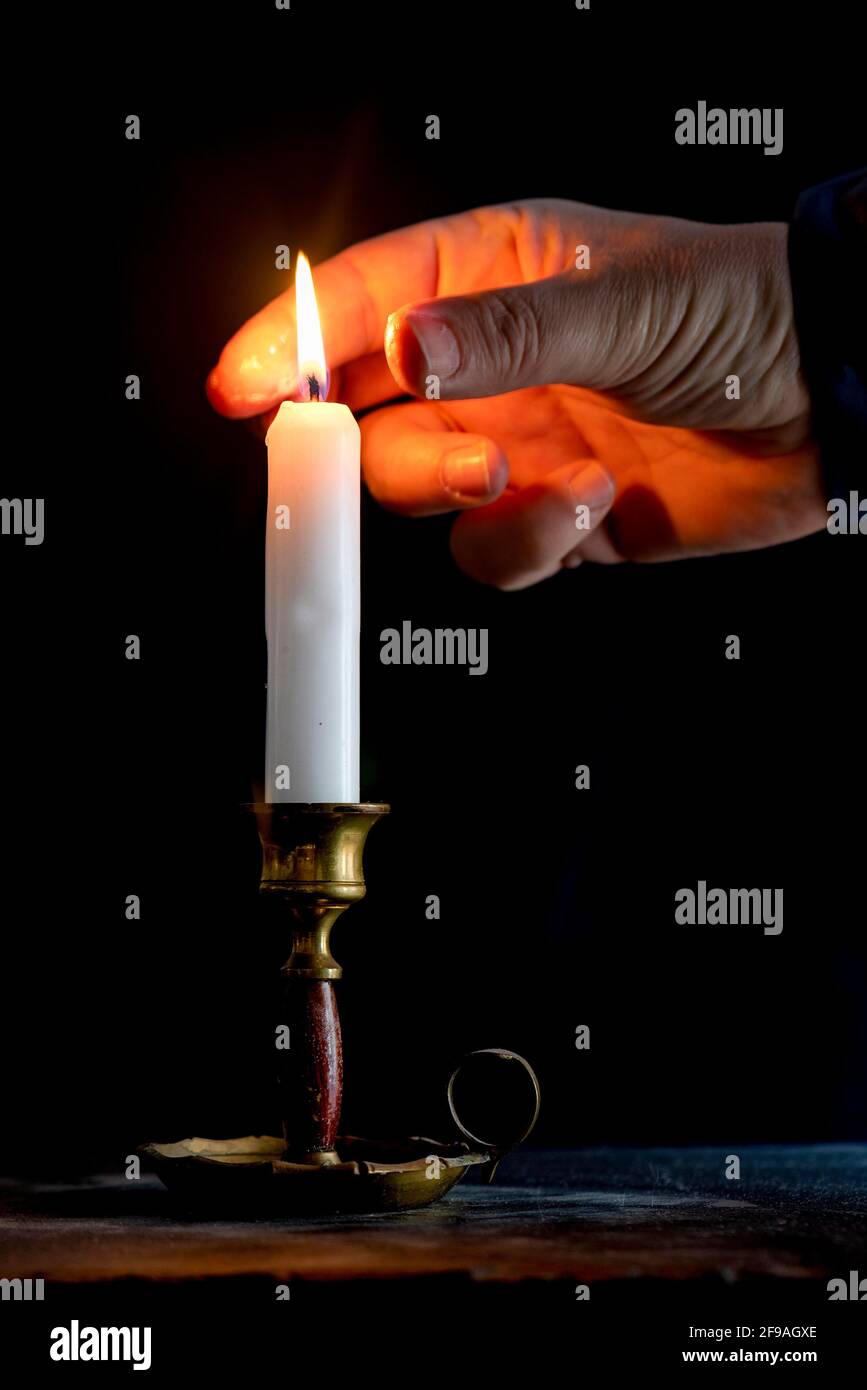 Man puts out candle with his thumb forefinger hires stock photography