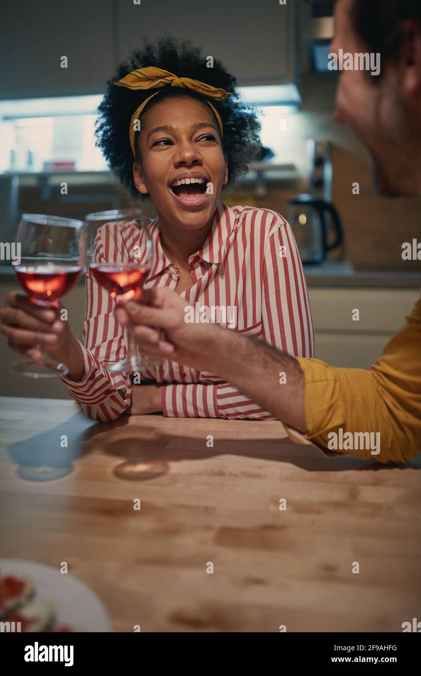 young afro-american woman amused by caucasian man, having toast, laughing. Stock Photo