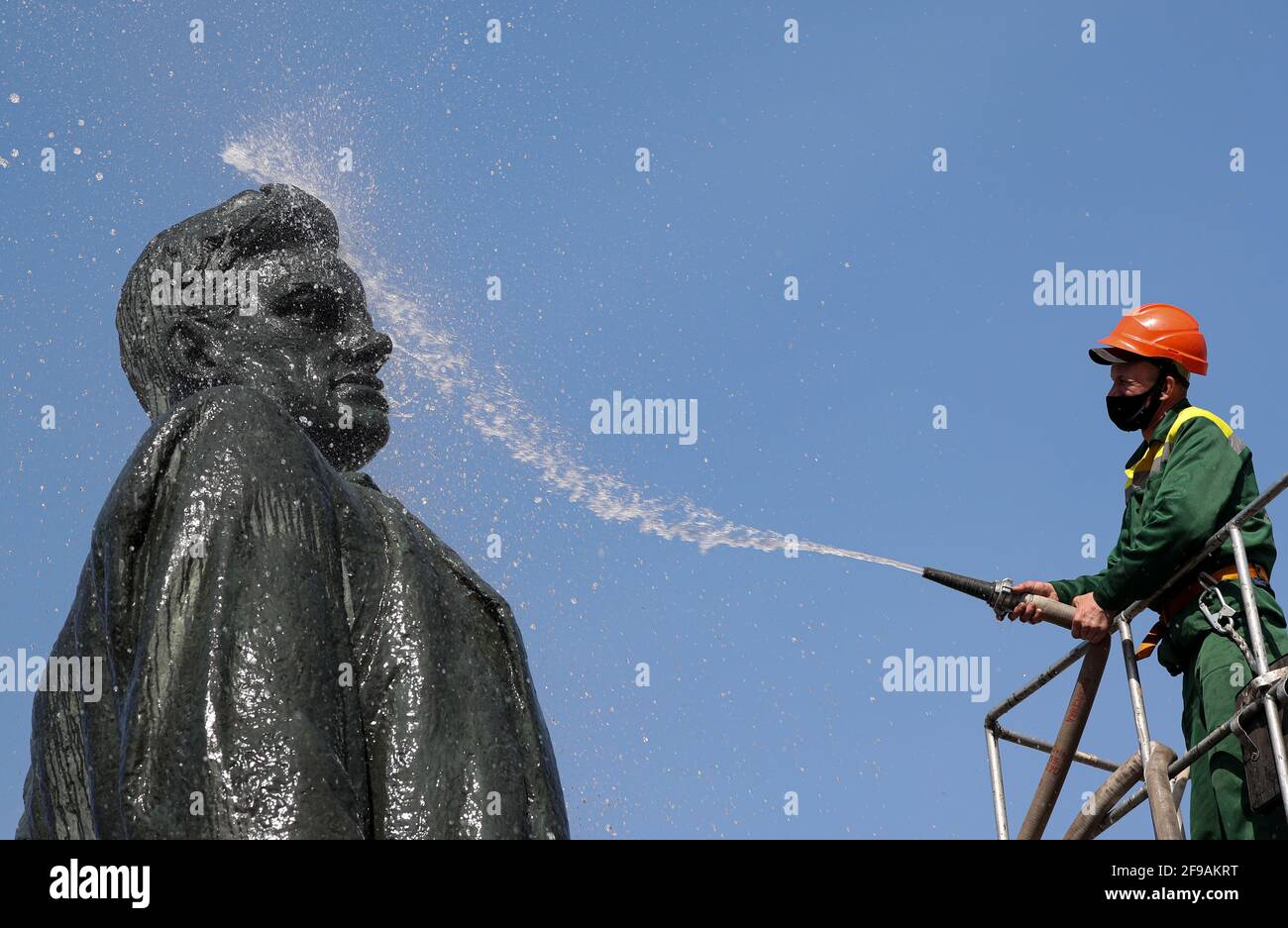 А municipal worker uses a pressure washer to clean a monument to Soviet poet Vladimir Mayakovsky in Moscow, Russia April 17, 2021.  REUTERS/Evgenia Novozhenina Stock Photo