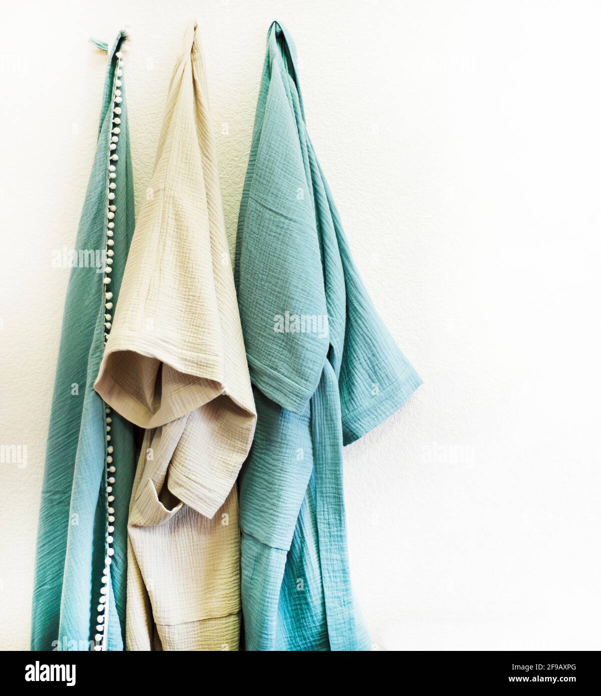 Bathrobes and organic cotton towels are hanging. Muslin home textiles. Stock Photo