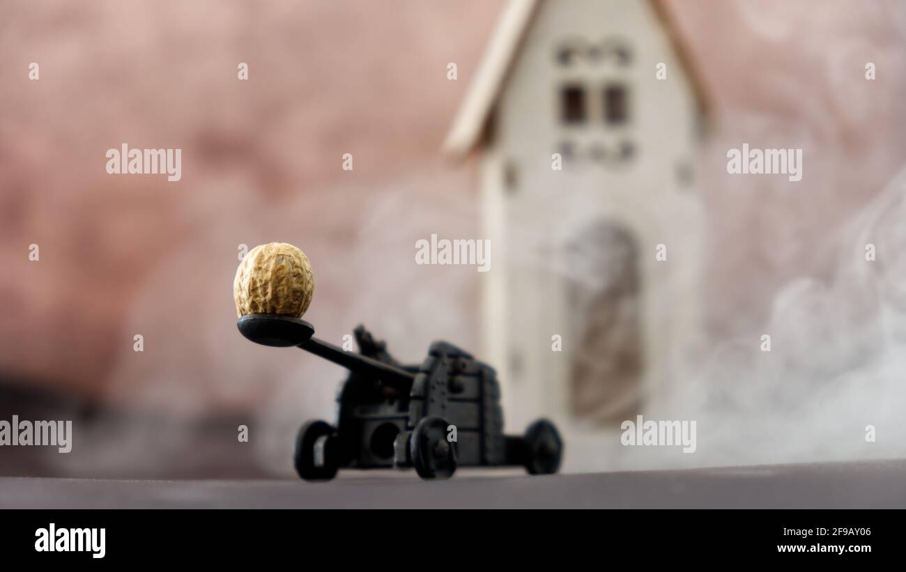 funny diorama of a catapult while pulling a peanut on a wooden house Stock Photo
