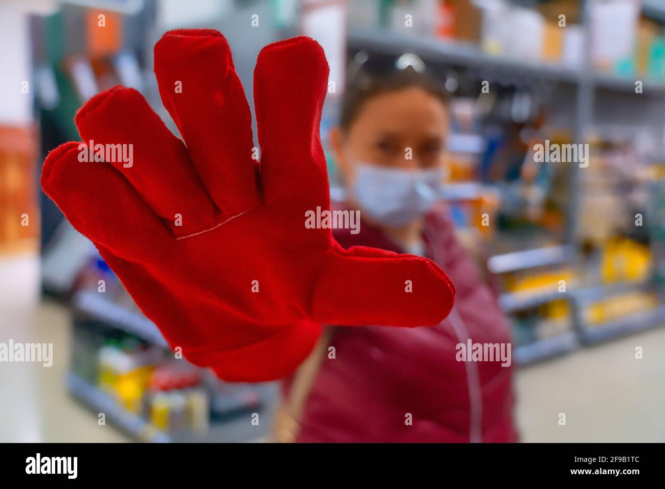 Batumi, Georgia - March 15, 2021: girl in a hardware store posing with red gloves Stock Photo