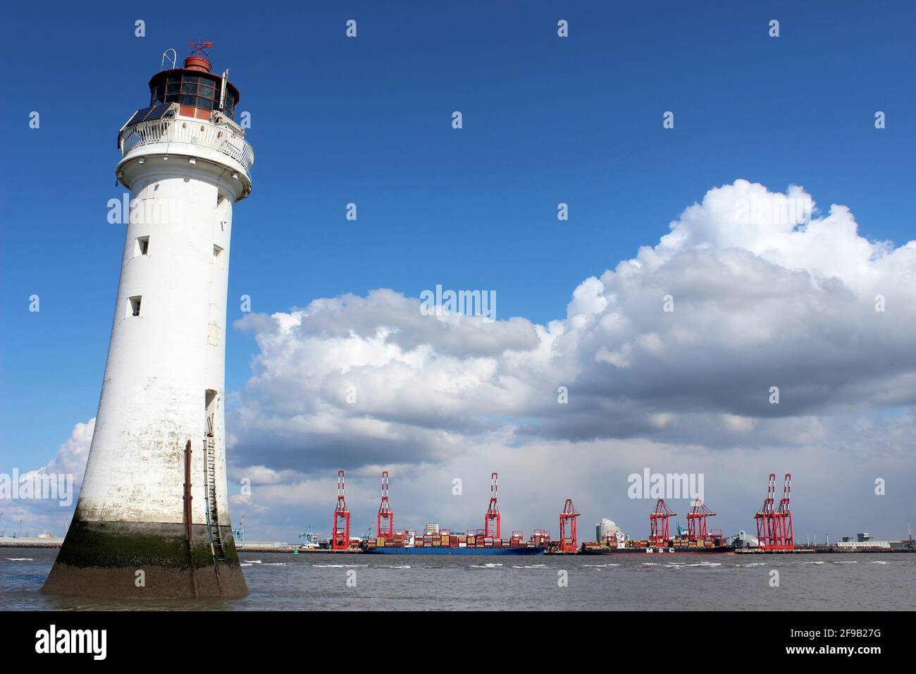 New Brighton Lighthouse with views across the River Mersey to Liverpool Docks and Liverpool2 Container Cranes Stock Photo