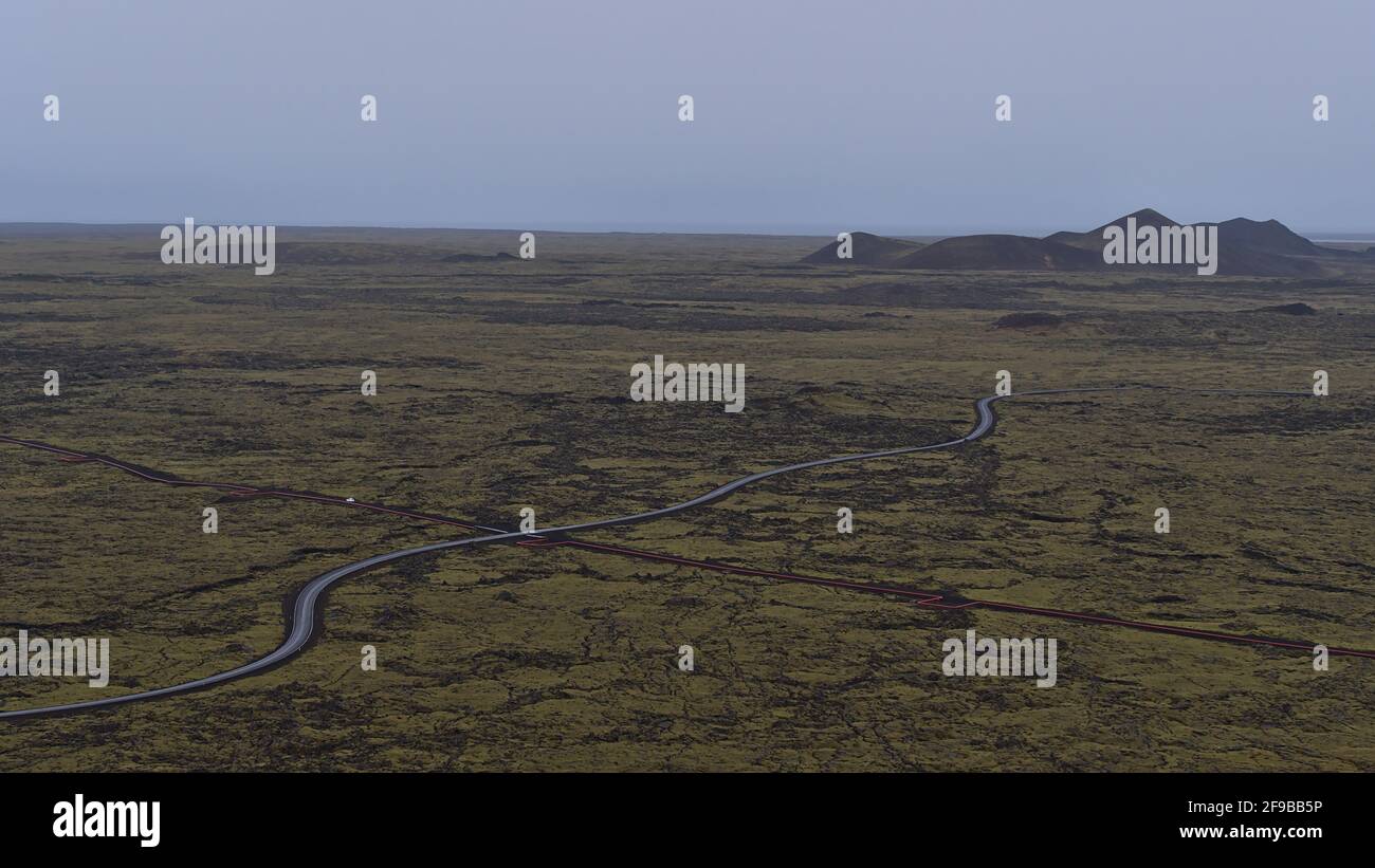 Aerial panorama view over the south of Reykjanes peninsula, Iceland with landscape of moss covered lava fields with winding road and pipeline. Stock Photo