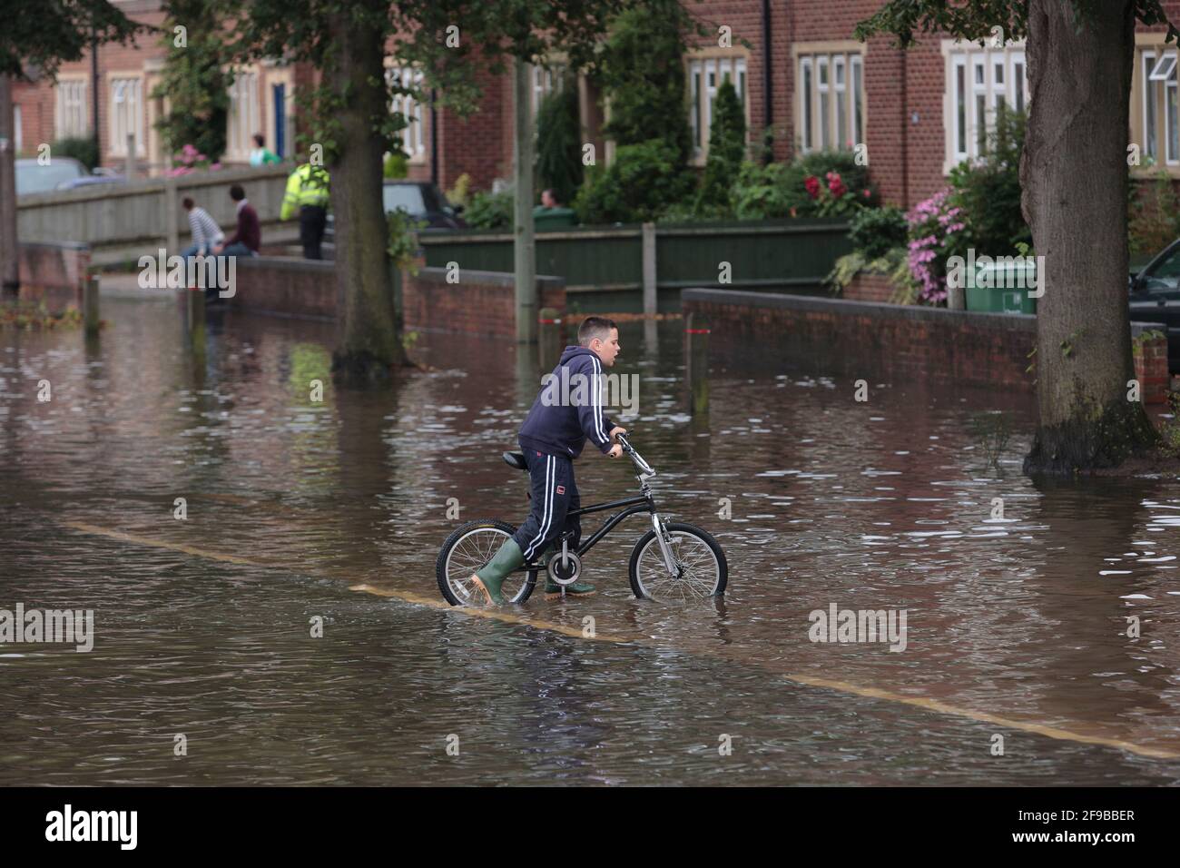 A boy cycling through flood waters hires stock photography and images