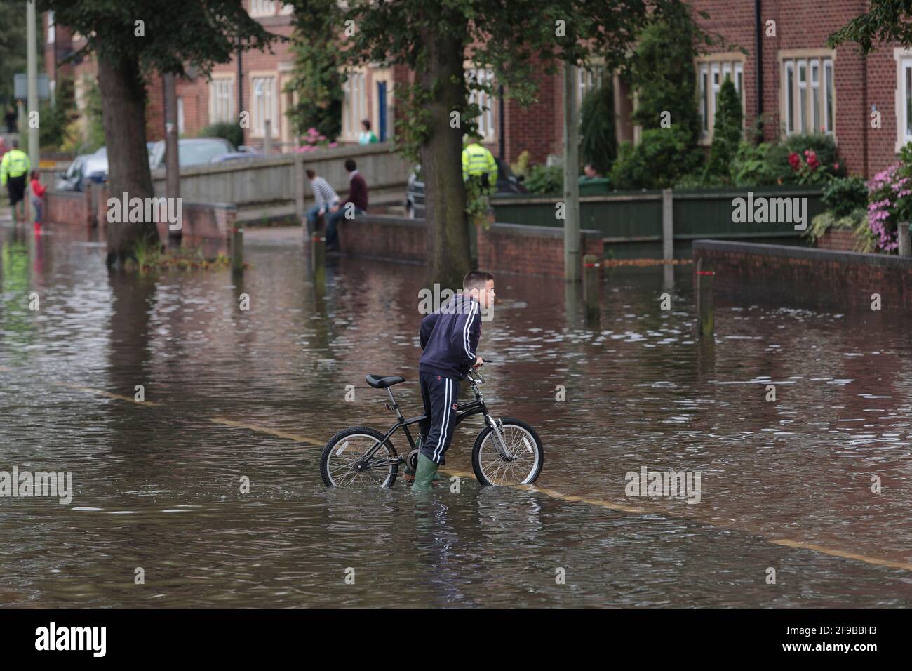 A boy cycling through flood waters hires stock photography and images