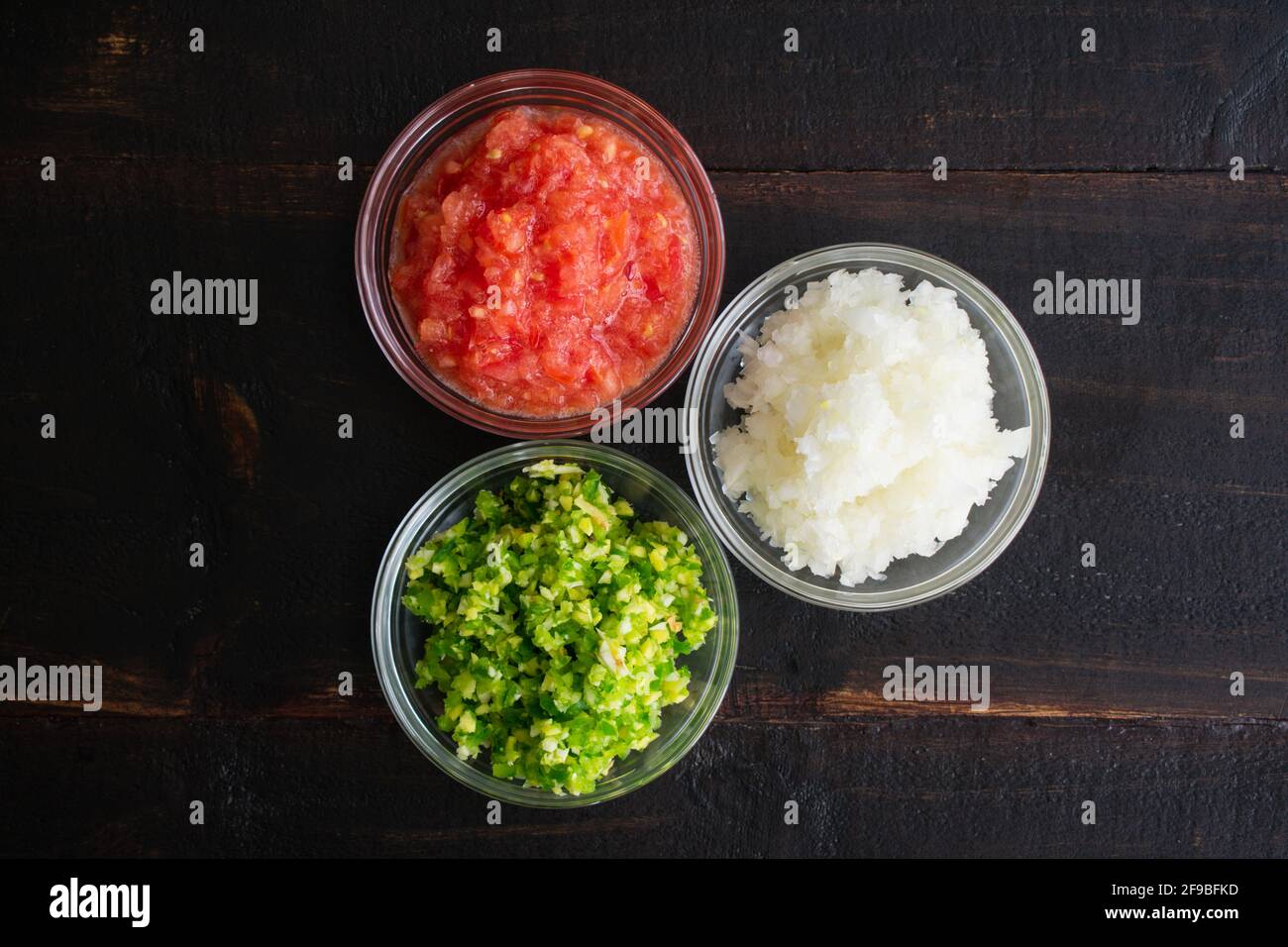 Bowls of Pureed Vegetables on a Wood Table: Pureed onions, tomatoes, green chili peppers, ginger, and garlic Stock Photo