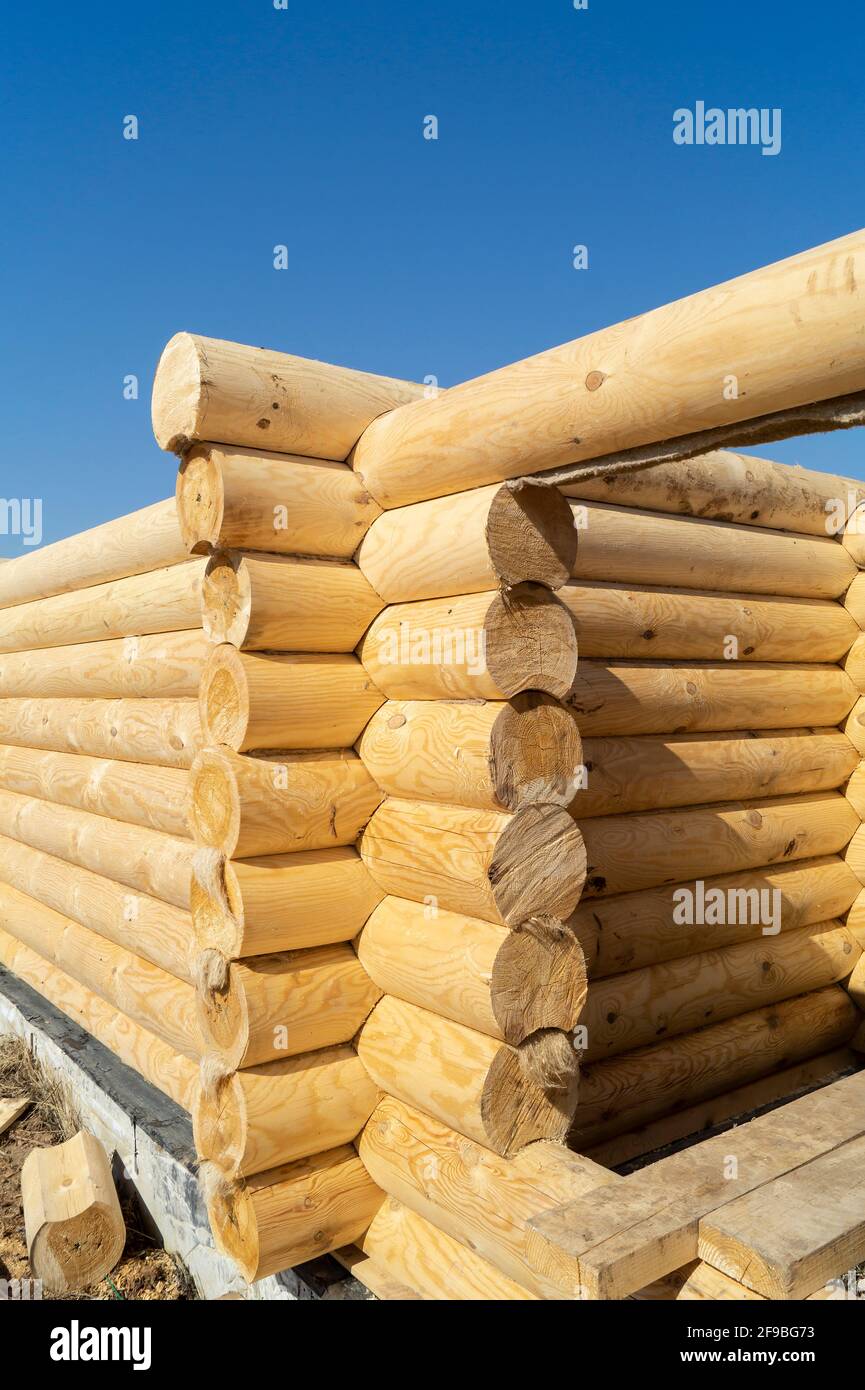 Construction of a wooden house on a sunny day in spring. New log house against the blue sky Stock Photo