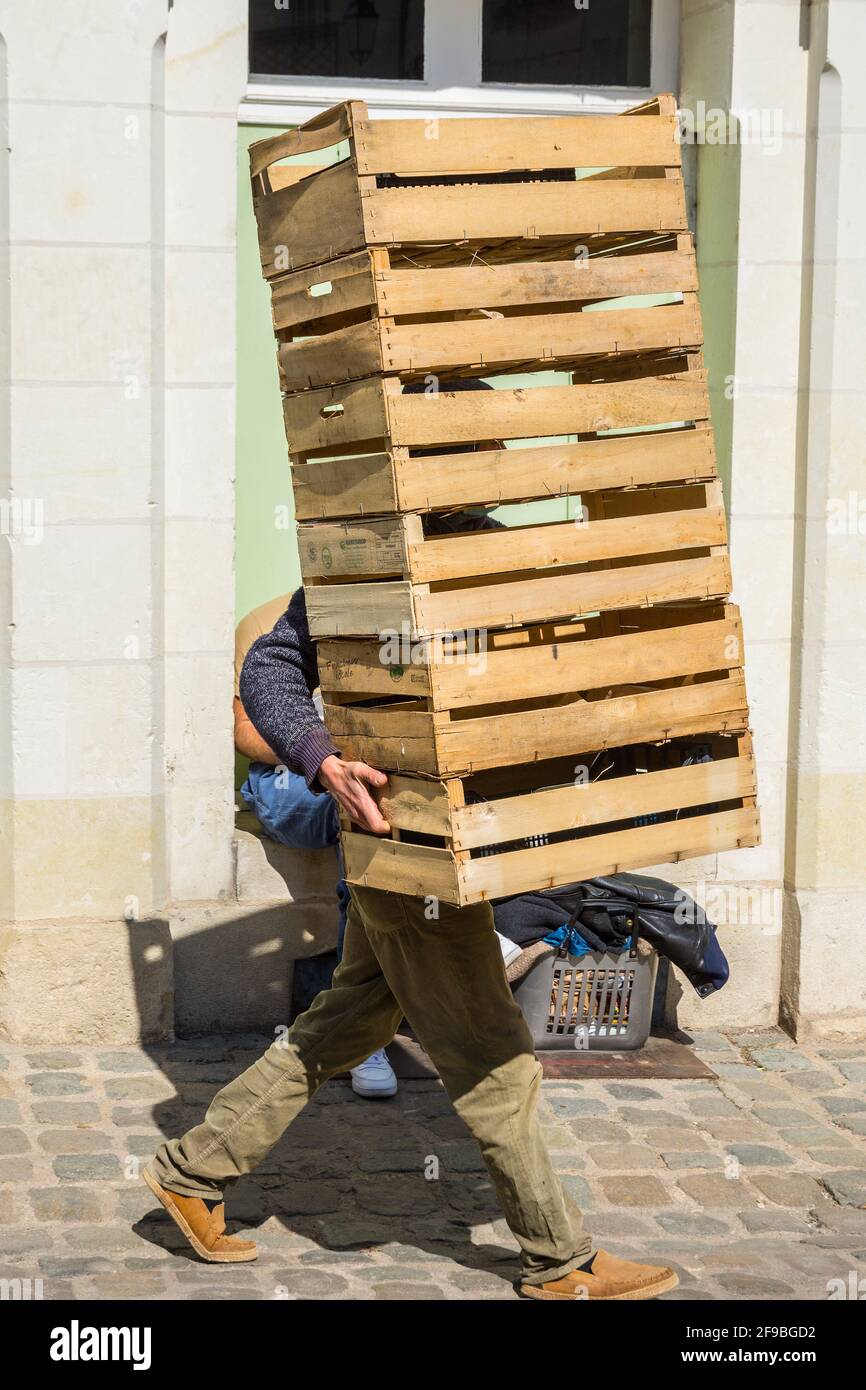 Market porter carrying stack of wooden boxes - Loches, Indre-et-Loire, France. Stock Photo