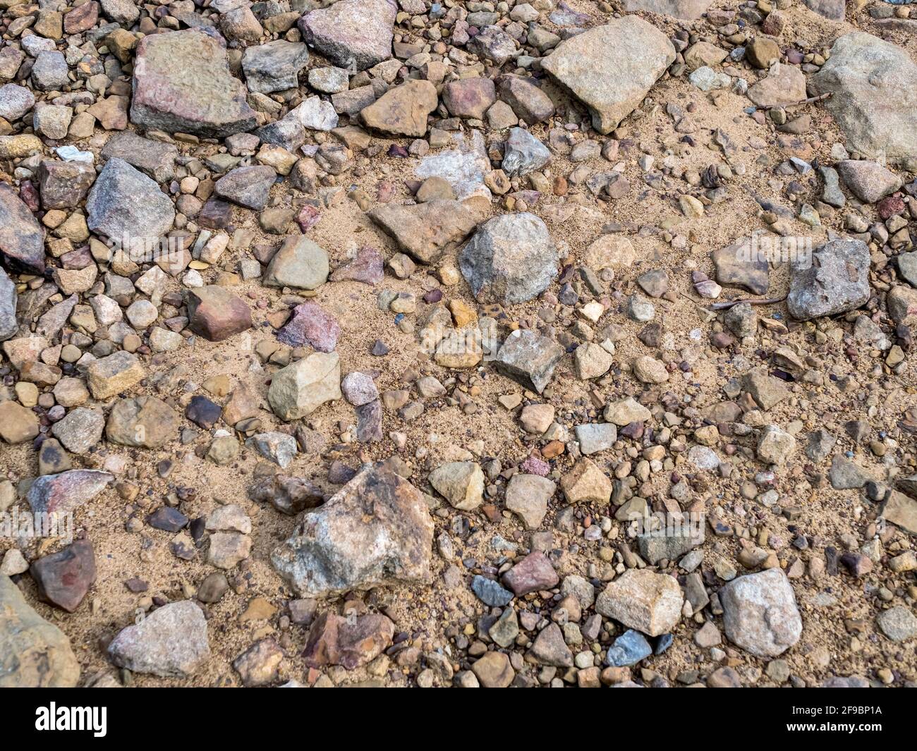 Sand and rocks up close for a background shot of a beach Stock Photo