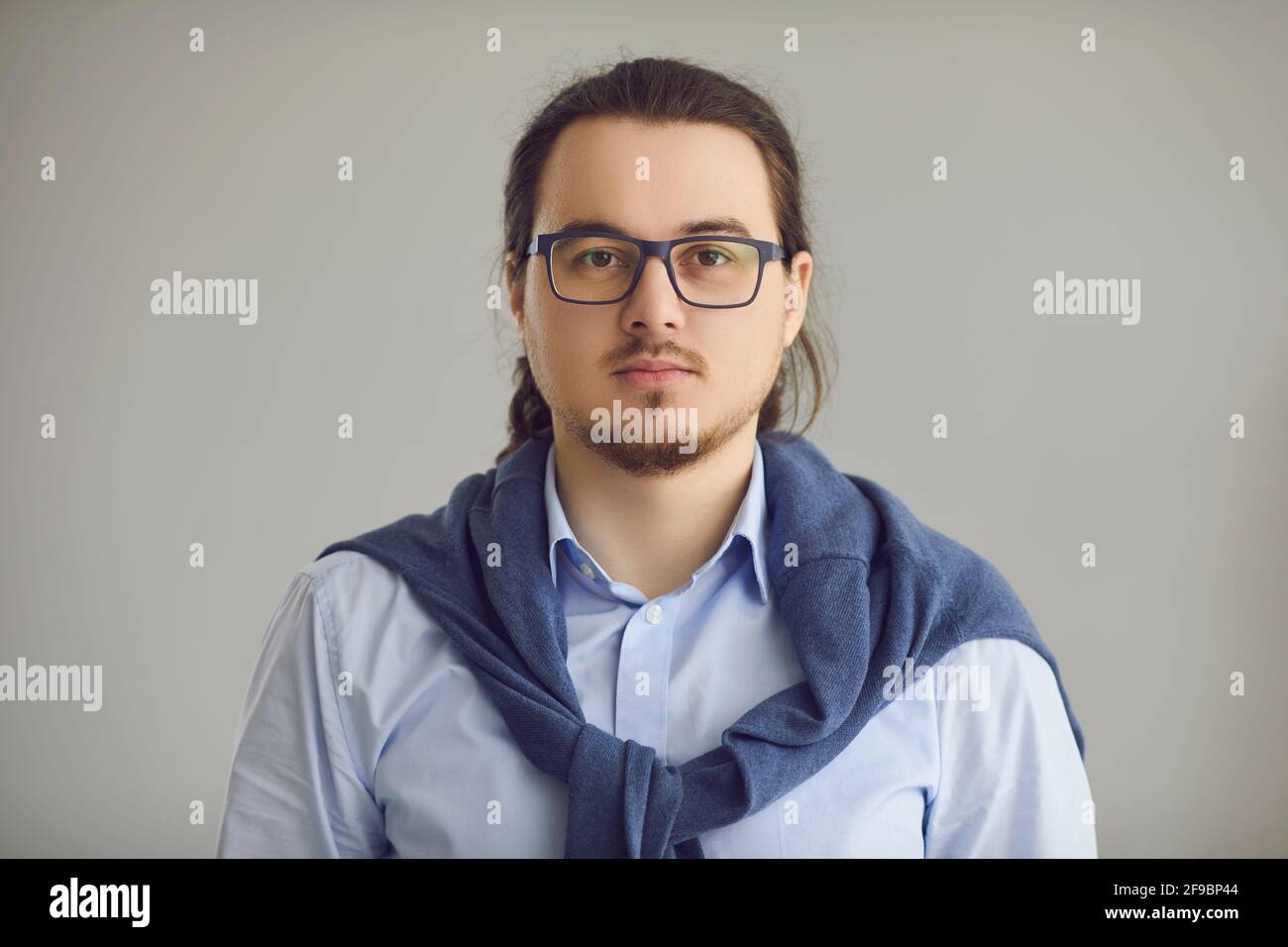 Studio headshot portrait of serious intelligent young man in office shirt and glasses Stock Photo