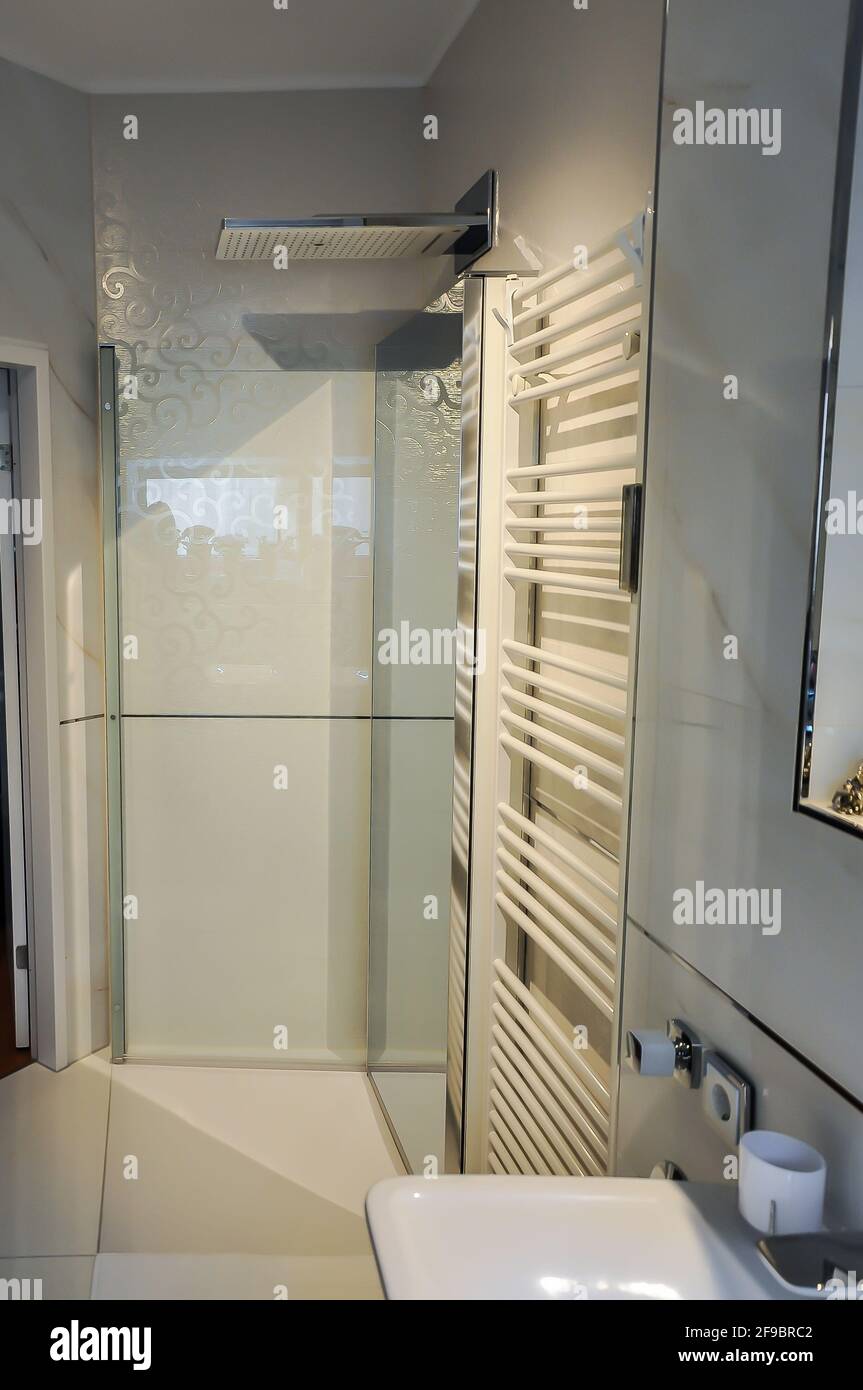 Floor-level shower with an exceptionally large overhead shower in a modern look. In the foreground a stylish towel radiator Stock Photo