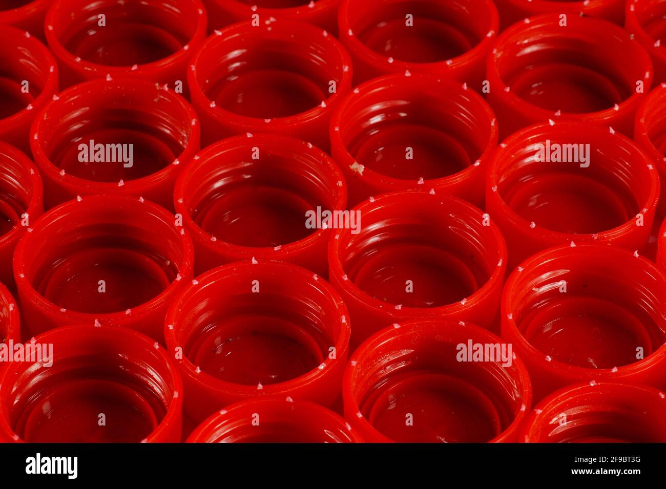 Red caps from bottles made of HDPE (high-density polyethylene) segregated according to colors prepared for recycling. Recyclable materials. Stock Photo