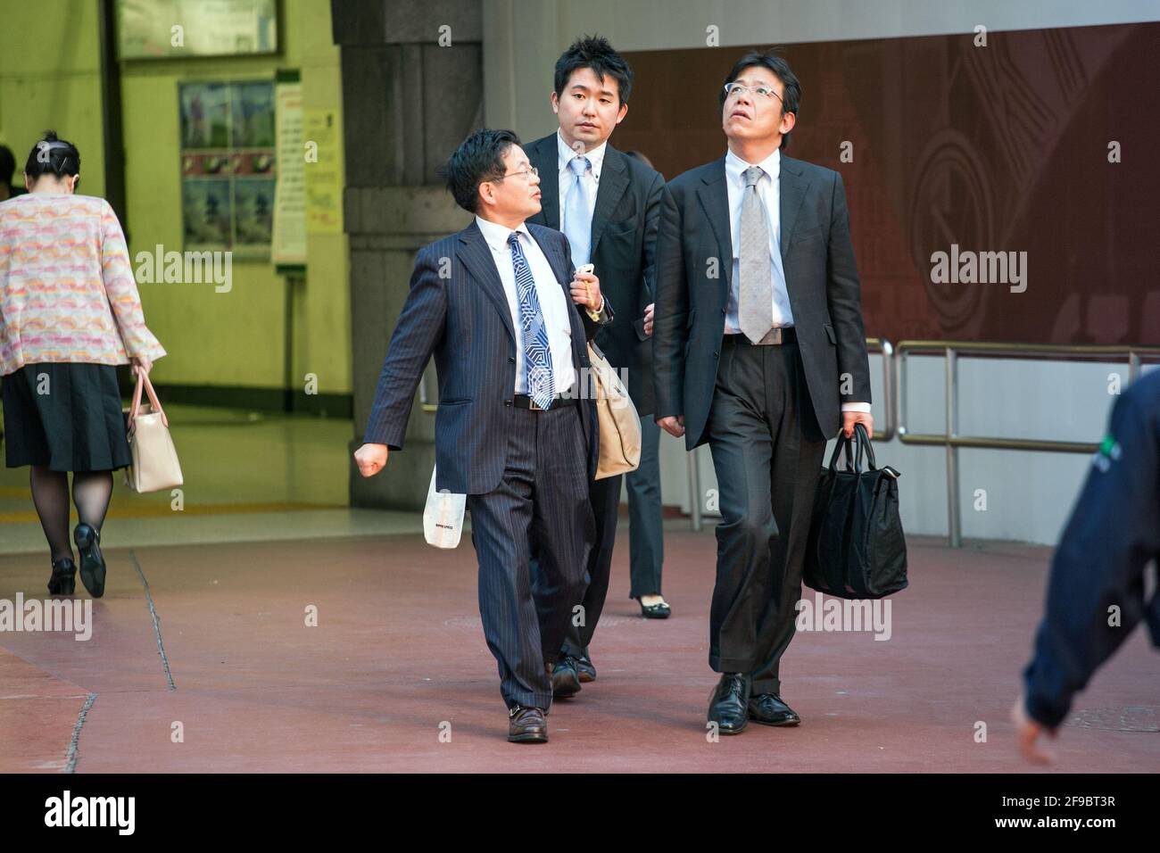 three-japanese-salarymen-walking-out-of-tokyo-station-into-the-heat-of-the-setting-sun-tokyo