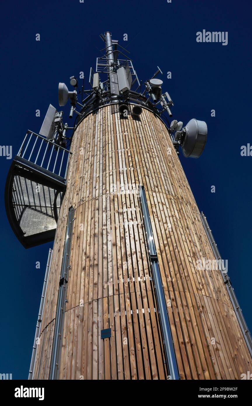 Stylish radio mast in front of a clear blue sky, with various antennas and clad with beautiful wooden panels. Stock Photo