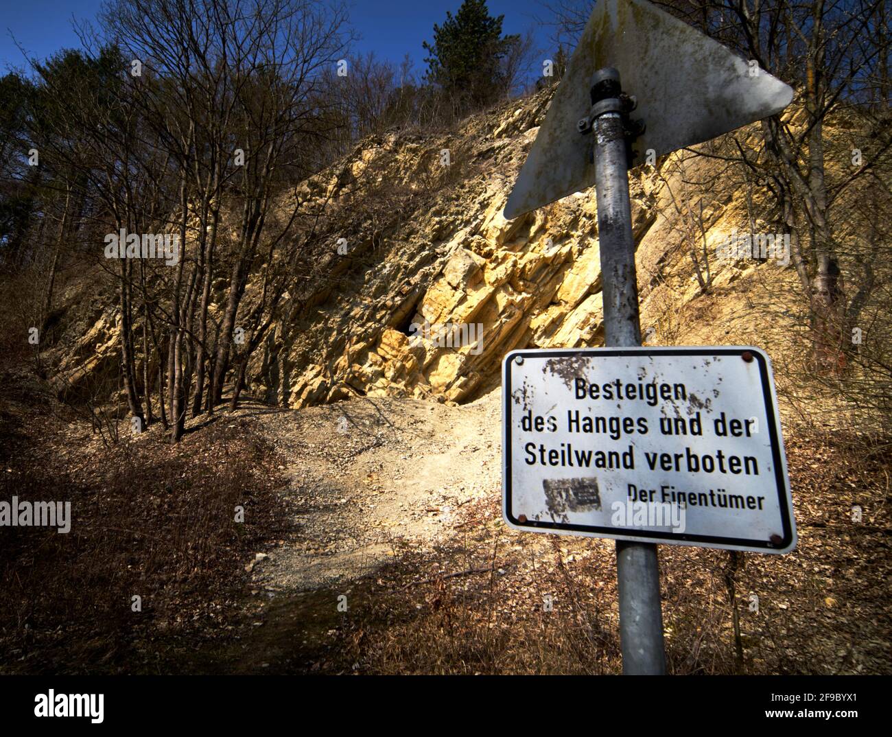 Sign with the German inscription: Climbing the slope and steep face forbidden, in front of an old limestone quarry Stock Photo