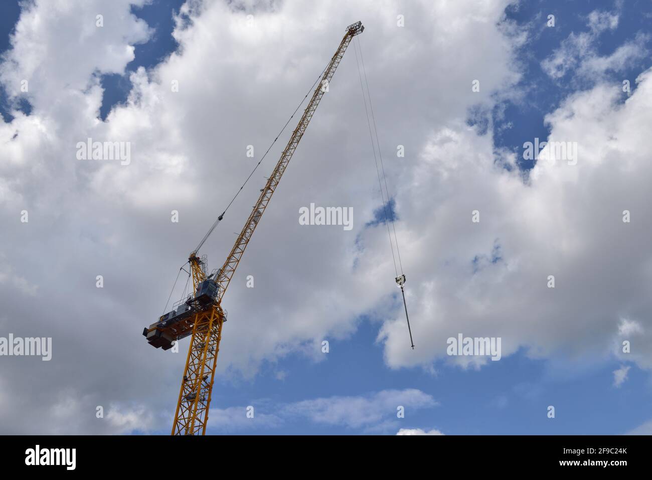 Tall construction crane against clouds in blue sky Stock Photo