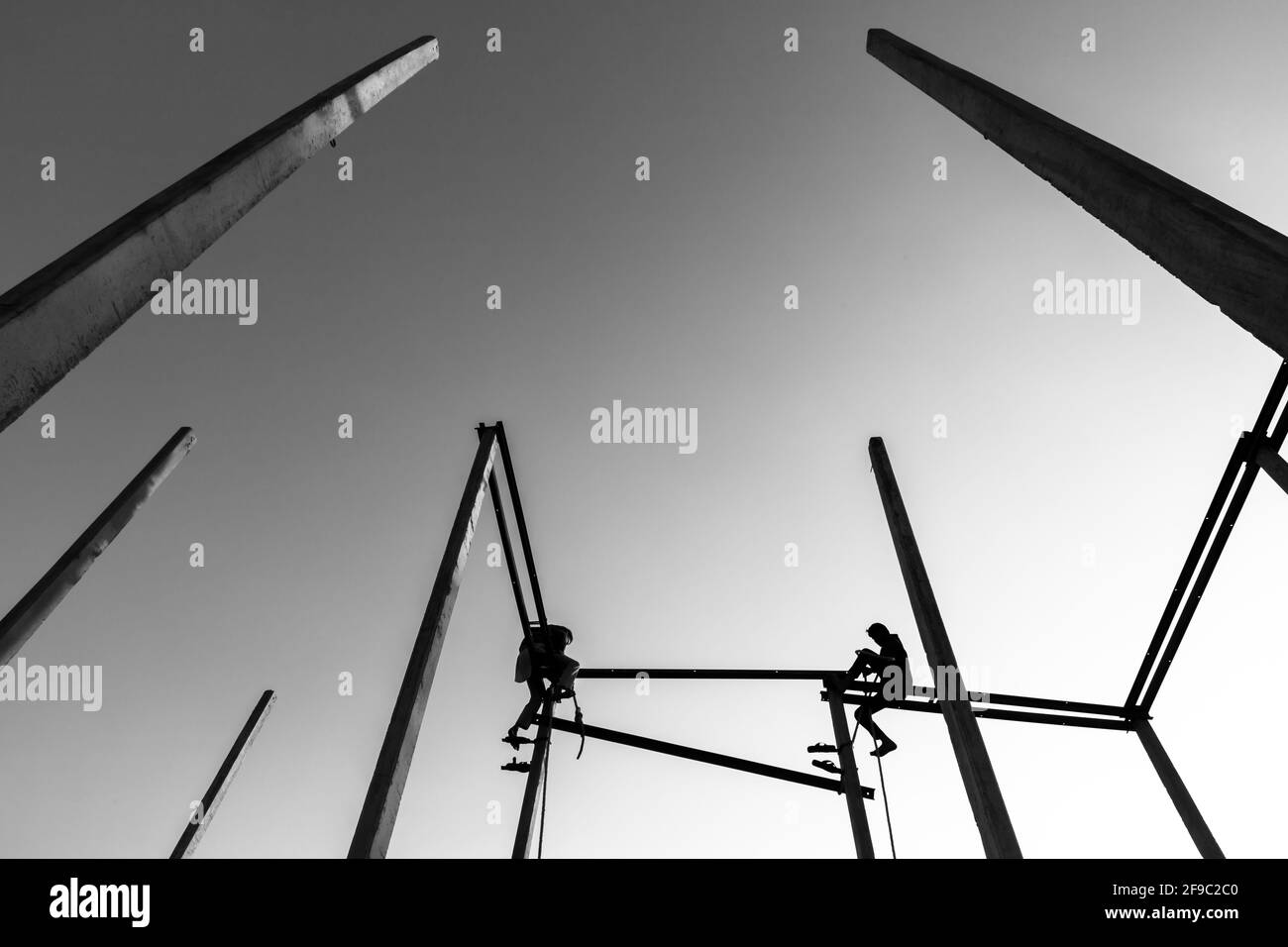 black and white silhouette of a two man sitting on electric pole. Stock Photo