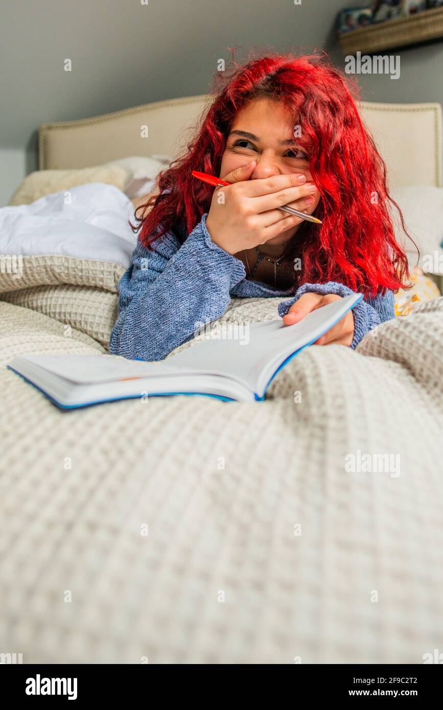 Gen Z Laughing to herself while writing in journal Stock Photo