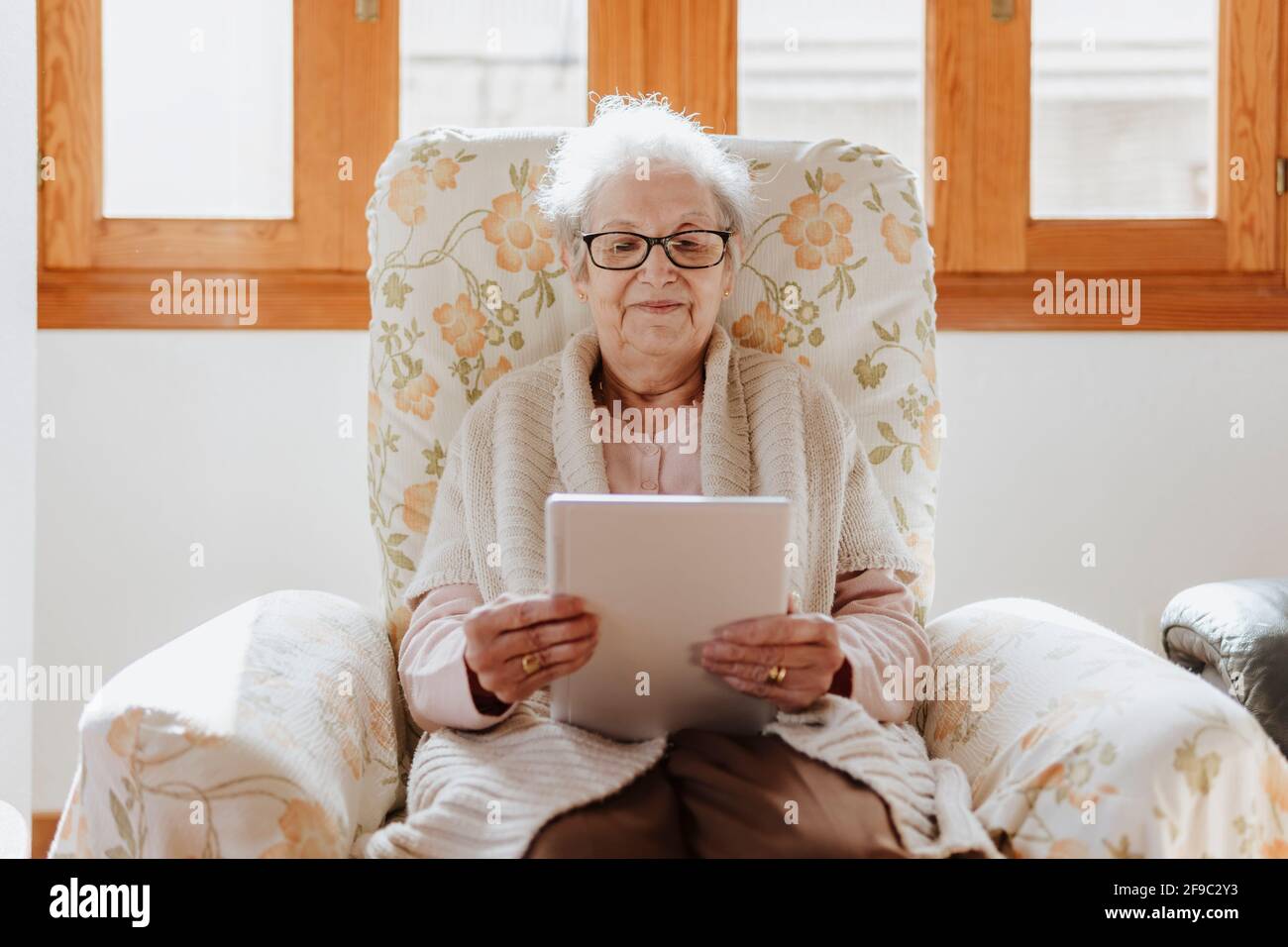 smiling elderly woman using a tablet on the sofa Stock Photo