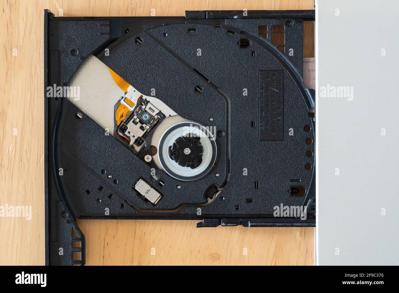A macro closeup on an external slim type CD DVD-ROM optical disk drive showing the pickup head (PUH), lens and tray Stock Photo