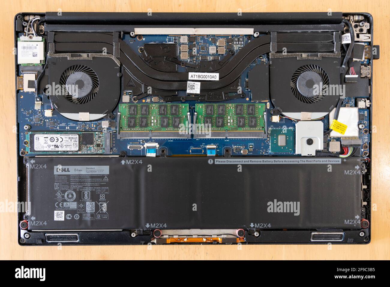 A Dell laptop with the case removed for maintenance on a table showing the fans, battery, electronic circuits and motherboard Stock Photo