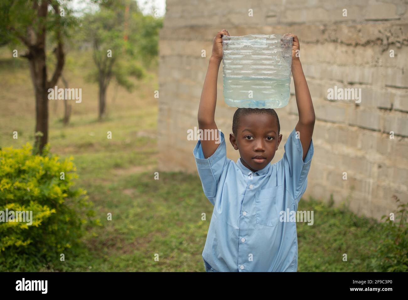 Dodoma, Tanzania. 08-18-2019. Black boy student is working at his rural school fetching drinking water for lunch. Stock Photo
