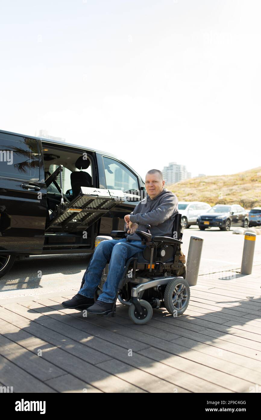 Disabled man close his wheelchair lift near car Stock Photo
