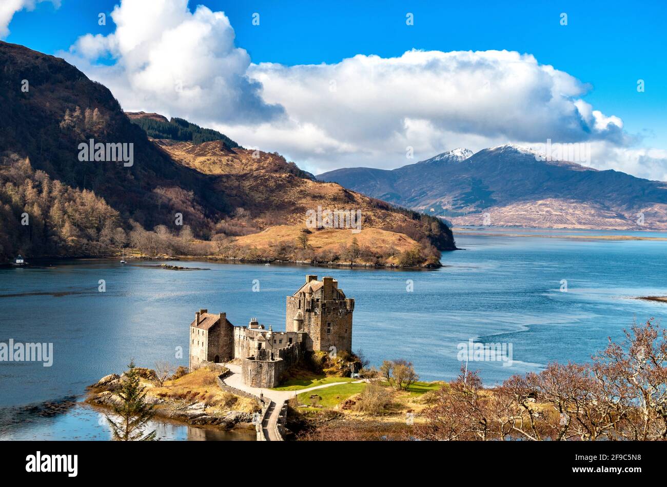 EILEAN DONAN CASTLE LOCH DUICH HIGHLANDS SCOTLAND IN SPRING SNOW CAPPED MOUNTAINS IN THE DISTANCE Stock Photo