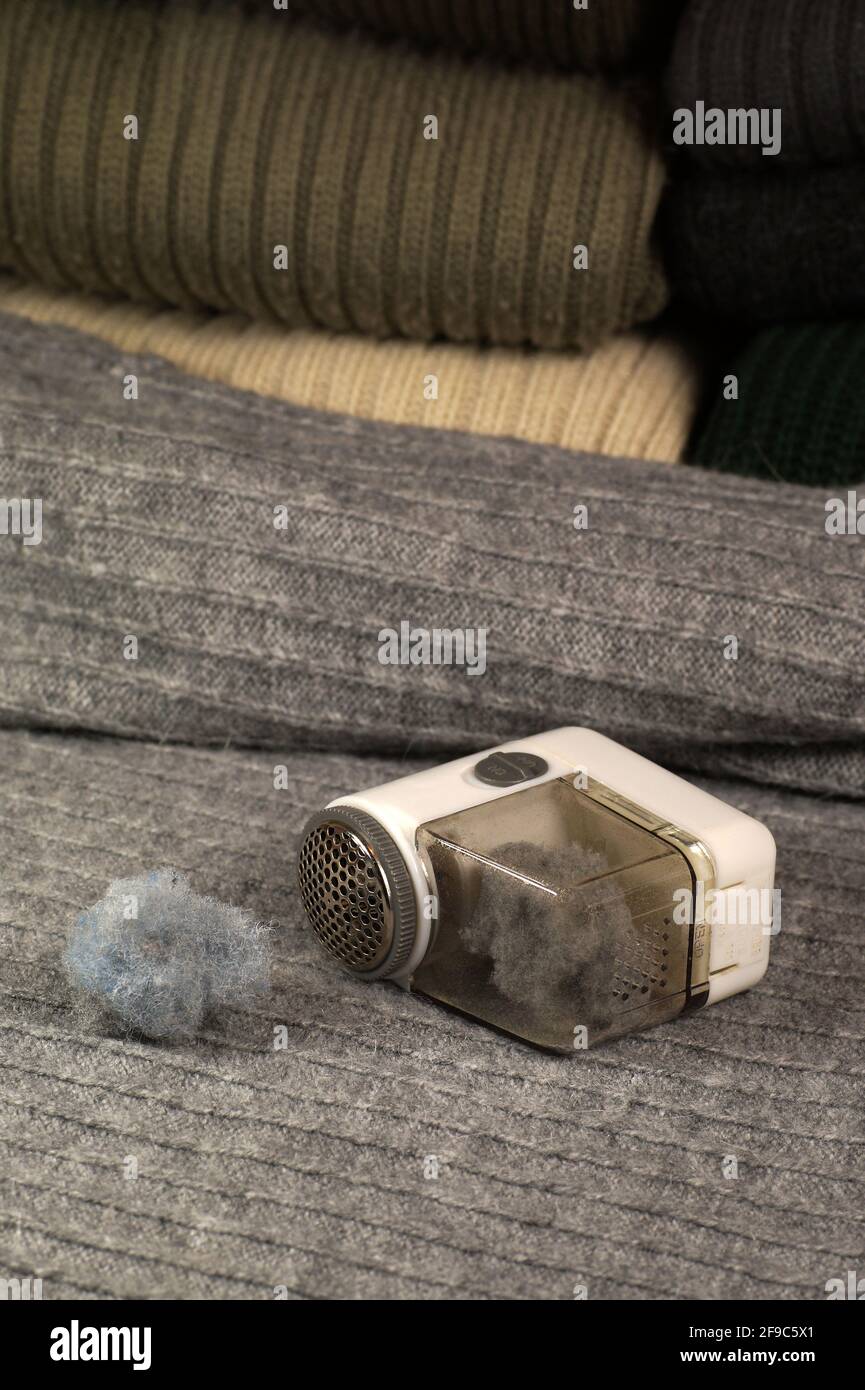 A few sweaters prepared for removing lint (pilling) and a device for removing them. Stock Photo