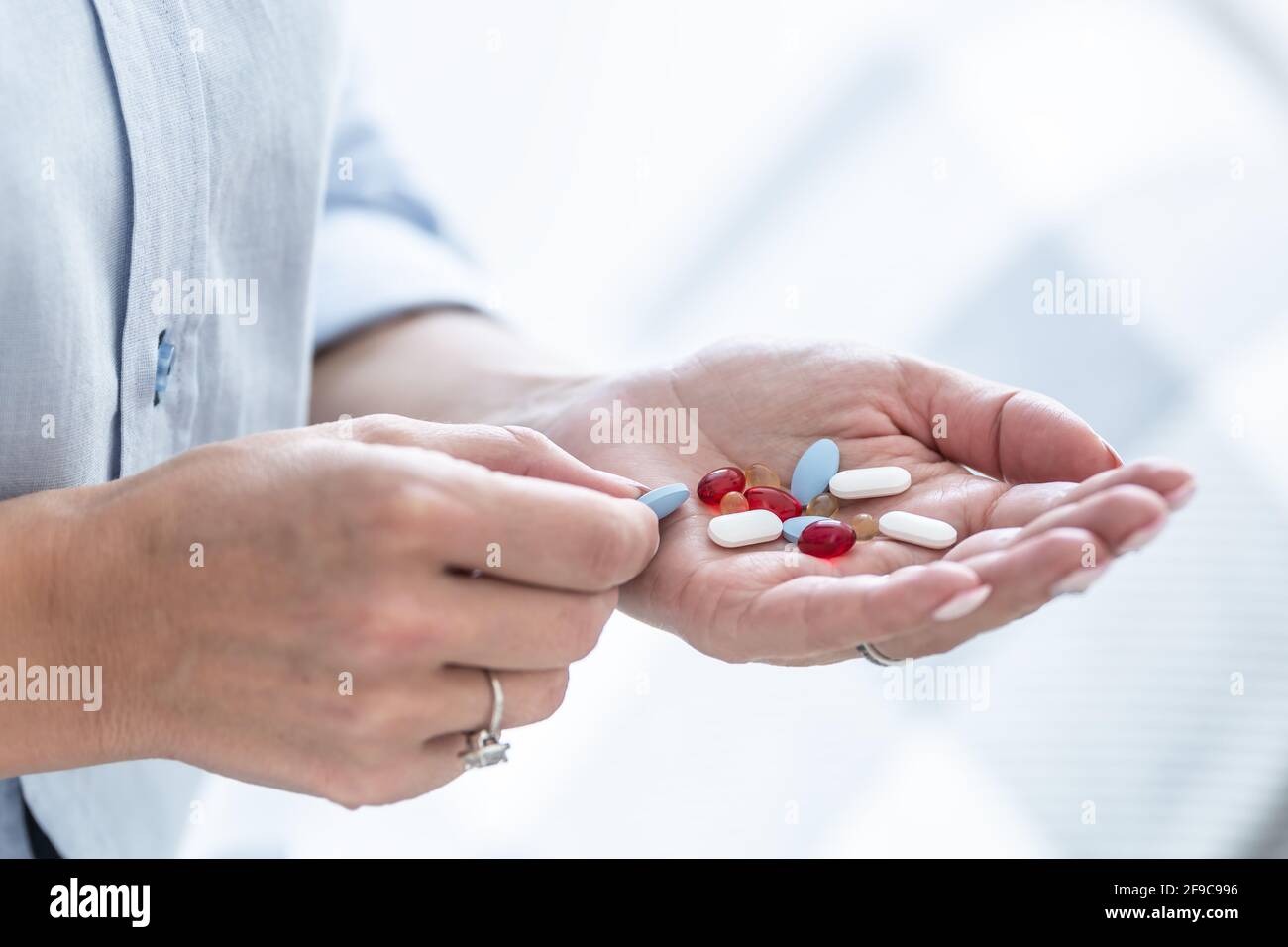 Female hand full of blue, white and red pills or supplements. Stock Photo