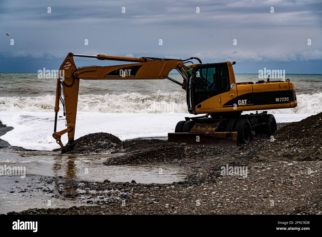 heavy yellow excavator working on the beach Stock Photo - Alamy