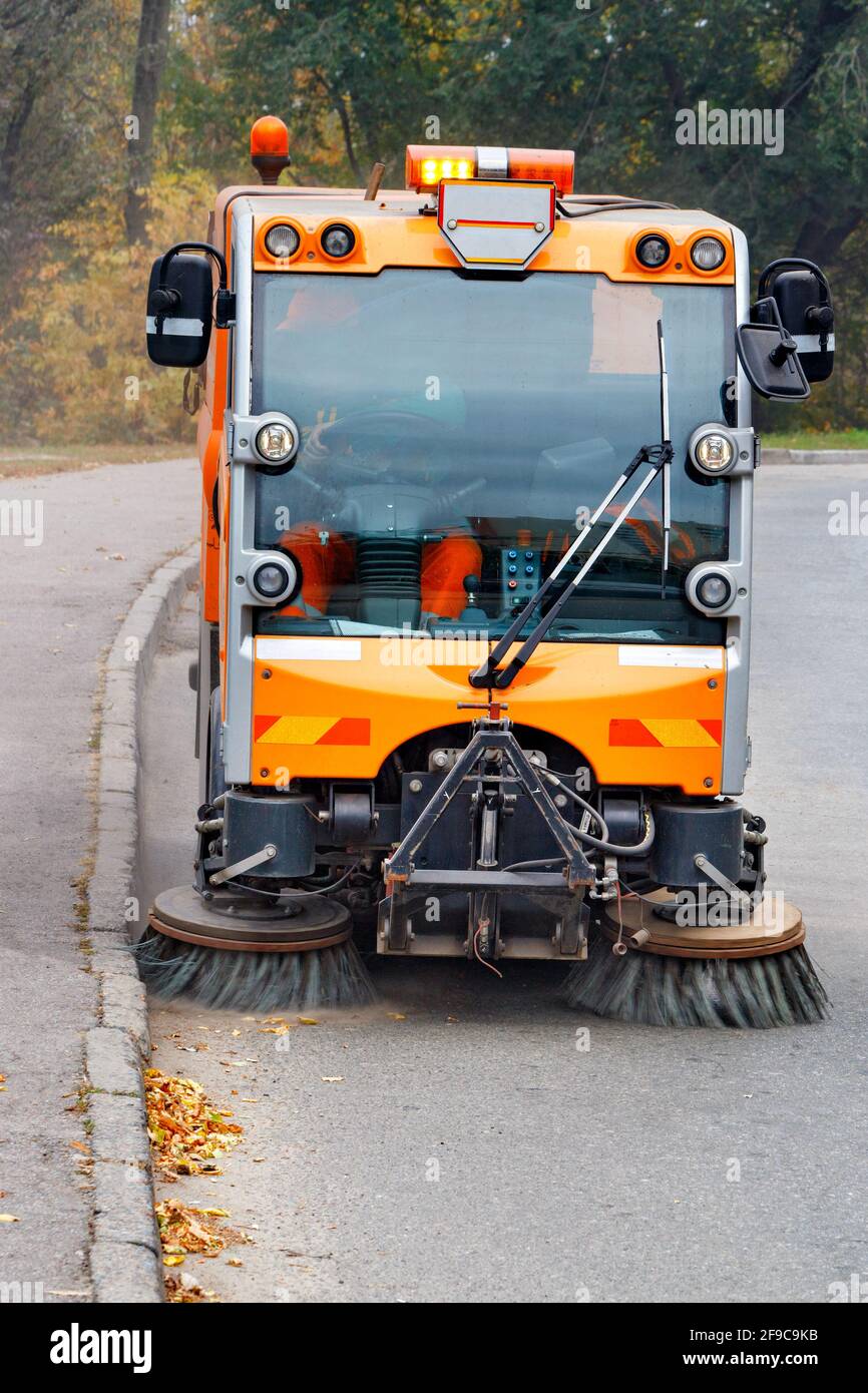 A municipal street sweeper car is sweeping the carriageway of a city