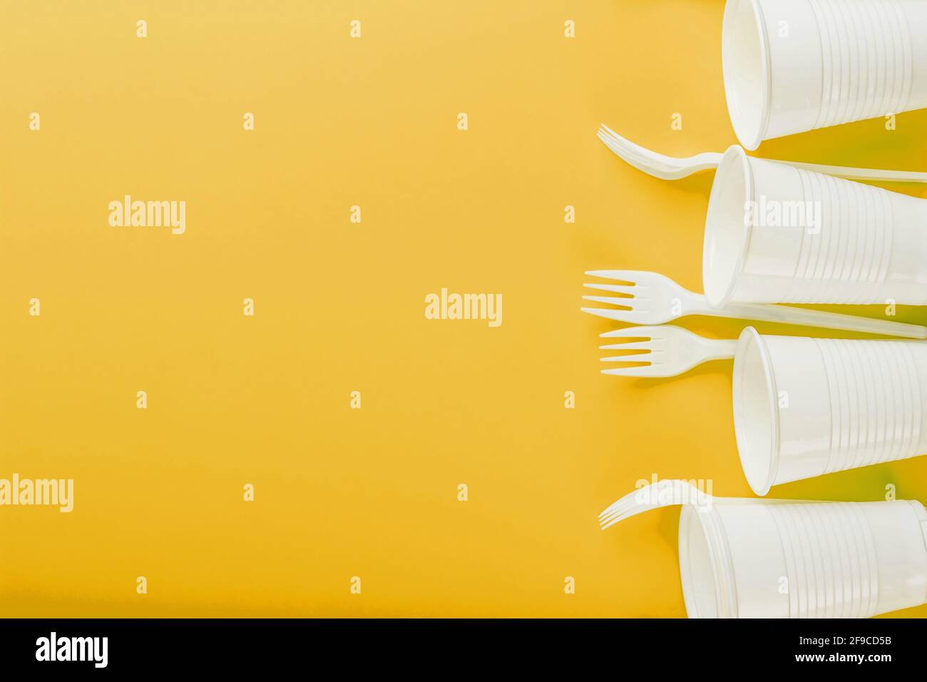 Plastic tableware on a yellow background with free space. Disposable tableware Stock Photo